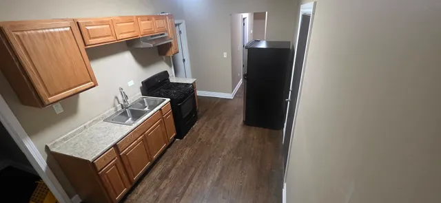 a kitchen with a refrigerator a sink and wooden floor