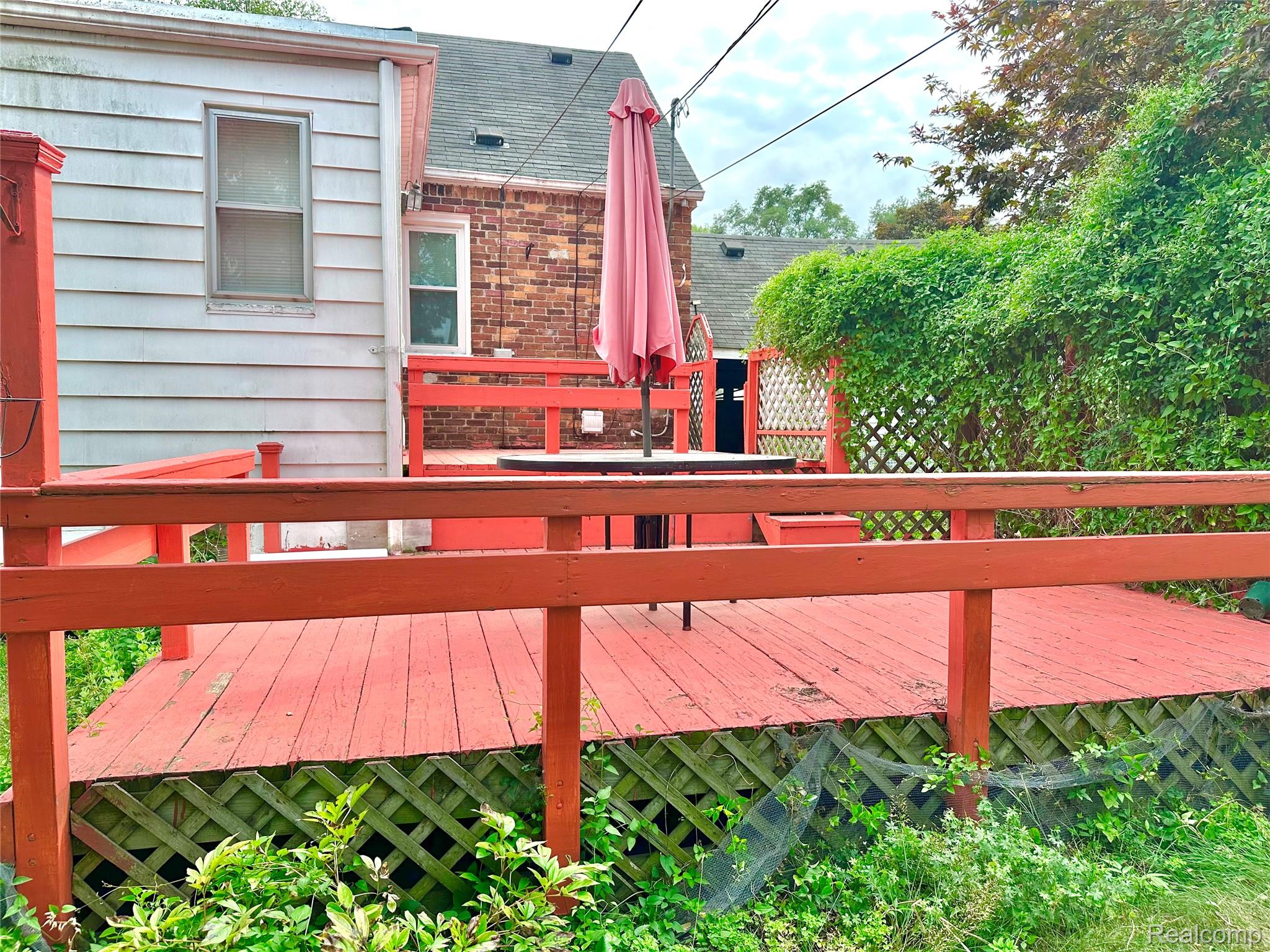 Expansive wooden deck with a red finish, integrated railing, and lattice skirting