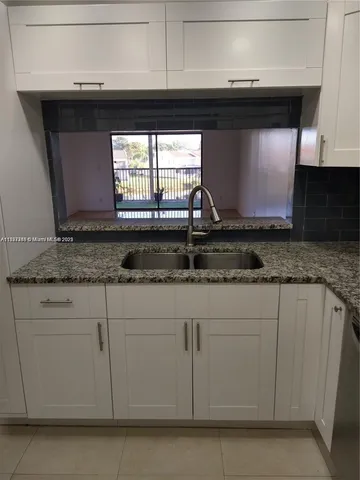 a kitchen with granite countertop white cabinets and a microwave