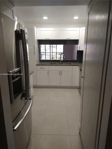 a view of a refrigerator in kitchen and windows