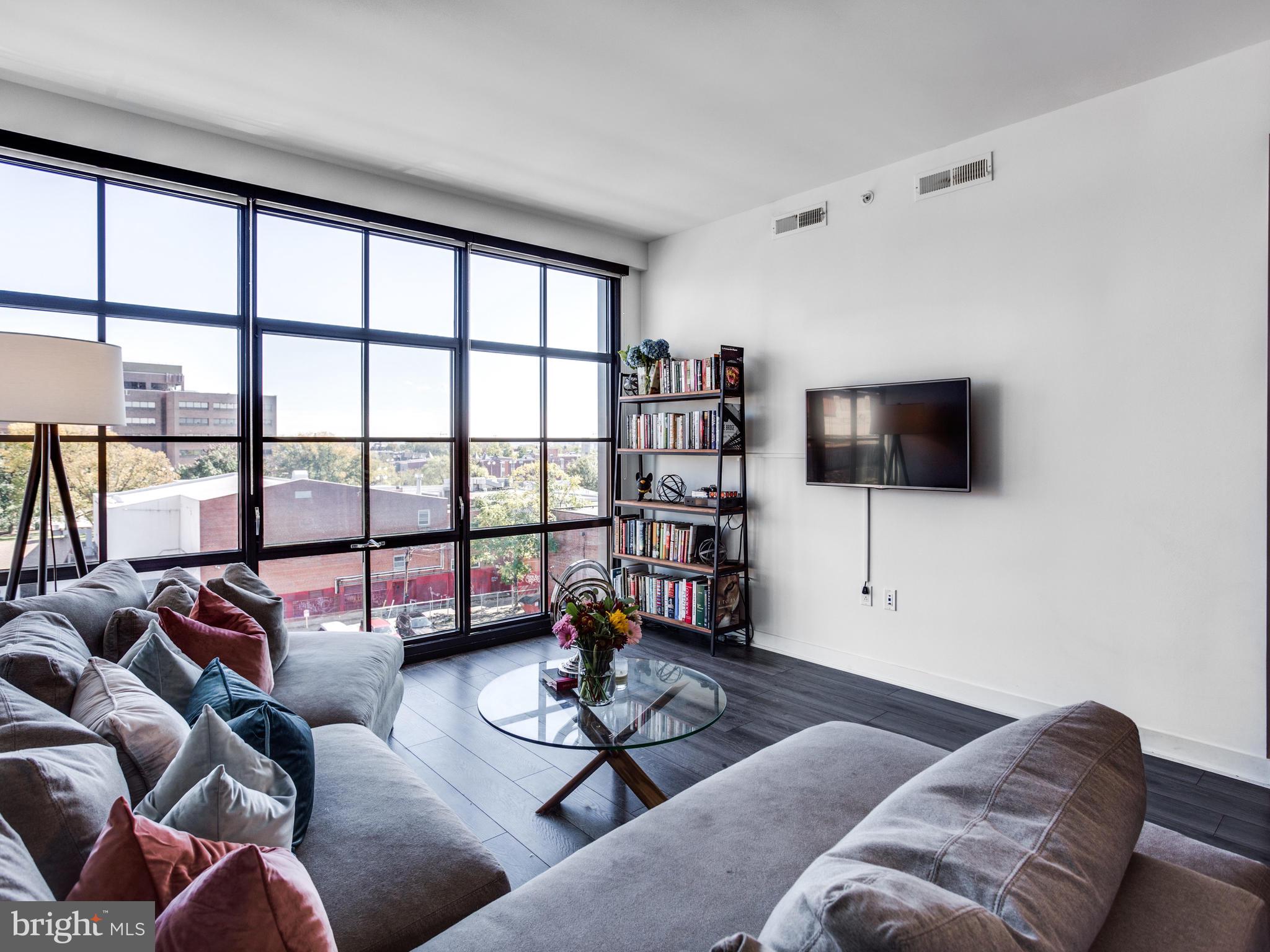 2030 8th Street Northwest, Unit 503 Washington, DC 20001 - Photo 12 of 31 a living room with furniture a flat screen tv and a floor to ceiling window