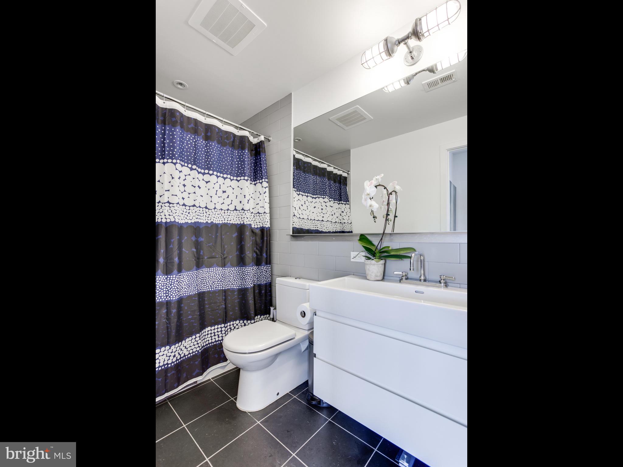 2030 8th Street Northwest, Unit 503 Washington, DC 20001 - Photo 16 of 31 a bathroom with a sink a toilet a mirror and shower