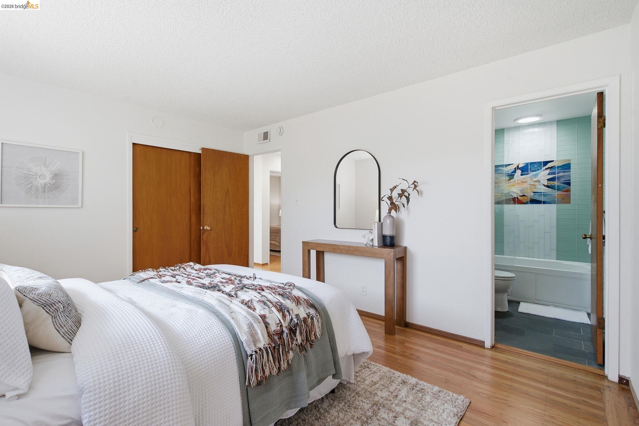 4522 Santa Rita Road El Sobrante, CA 94803 - Photo 22 of 58 Hardwood-finish flooring, built-in closet with wood doors, white interior walls, and an ensuite bathroom featuring a tub and tiled walls