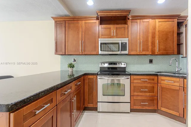 a kitchen with granite countertop cabinets stainless steel appliances and a sink
