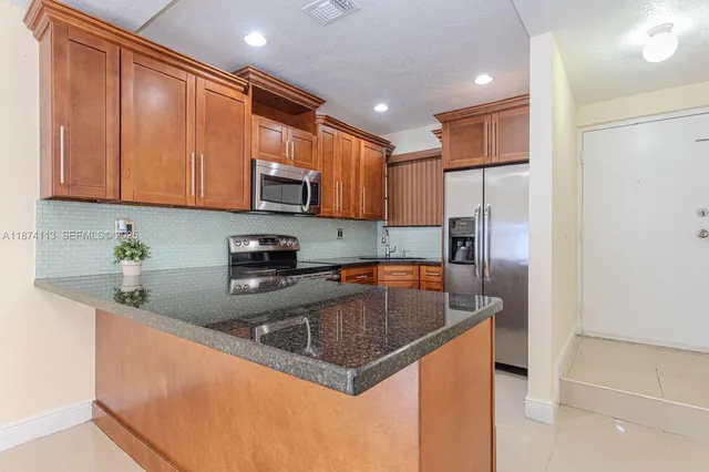 a kitchen with stainless steel appliances granite countertop a sink a refrigerator and a granite counter tops