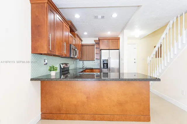 a kitchen with stainless steel appliances granite countertop a sink a stove and a refrigerator