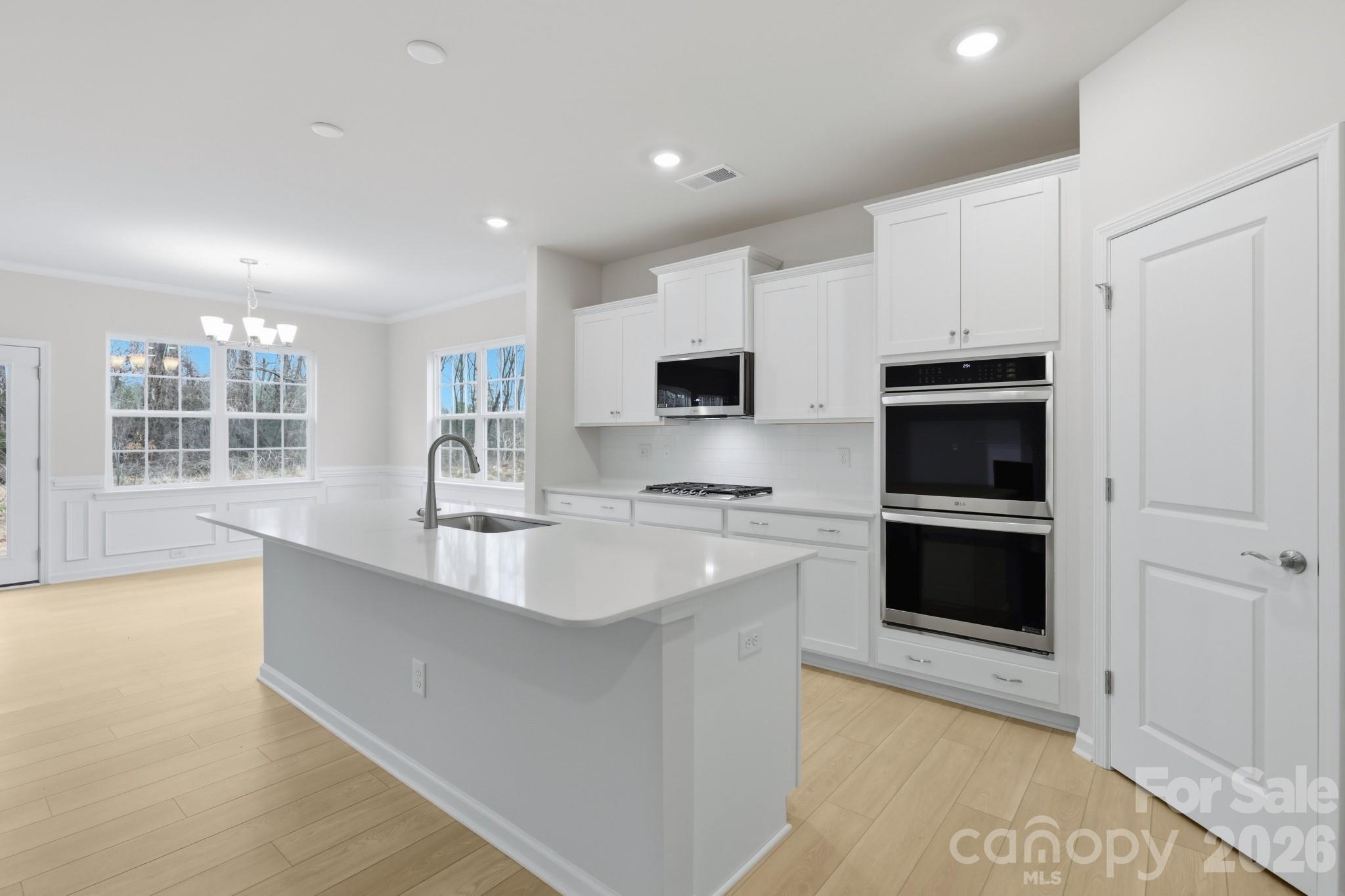 5450 Redbud Road, Unit 66 Lancaster, SC 29720 - Photo 16 of 35 a large white kitchen with stainless steel appliances granite countertop a stove a sink and a microwave