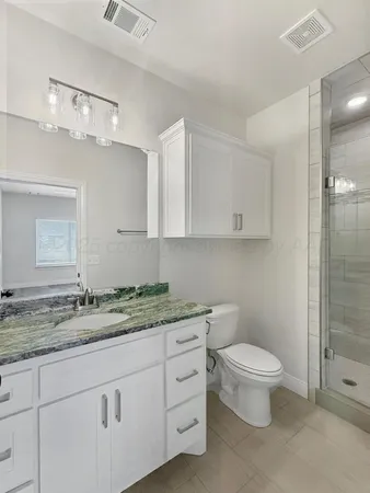 a bathroom with a granite countertop toilet sink and mirror
