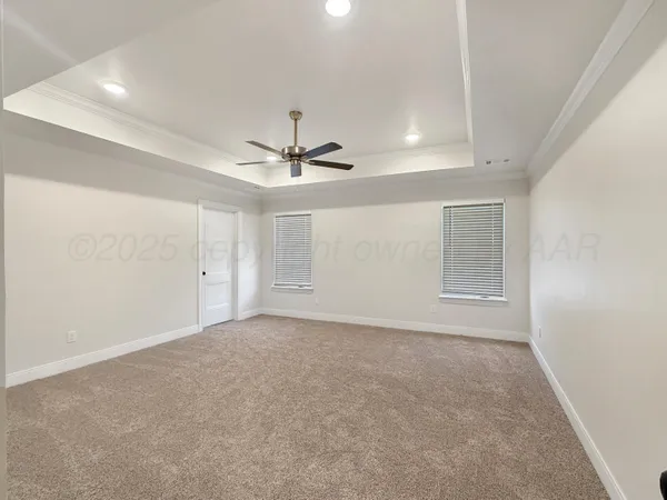 a view of an empty room with chandelier fan and fire place
