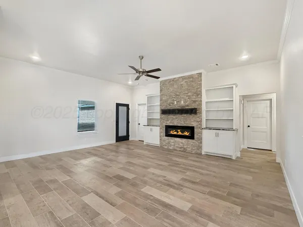 a view of an empty room with a fireplace and a kitchen view