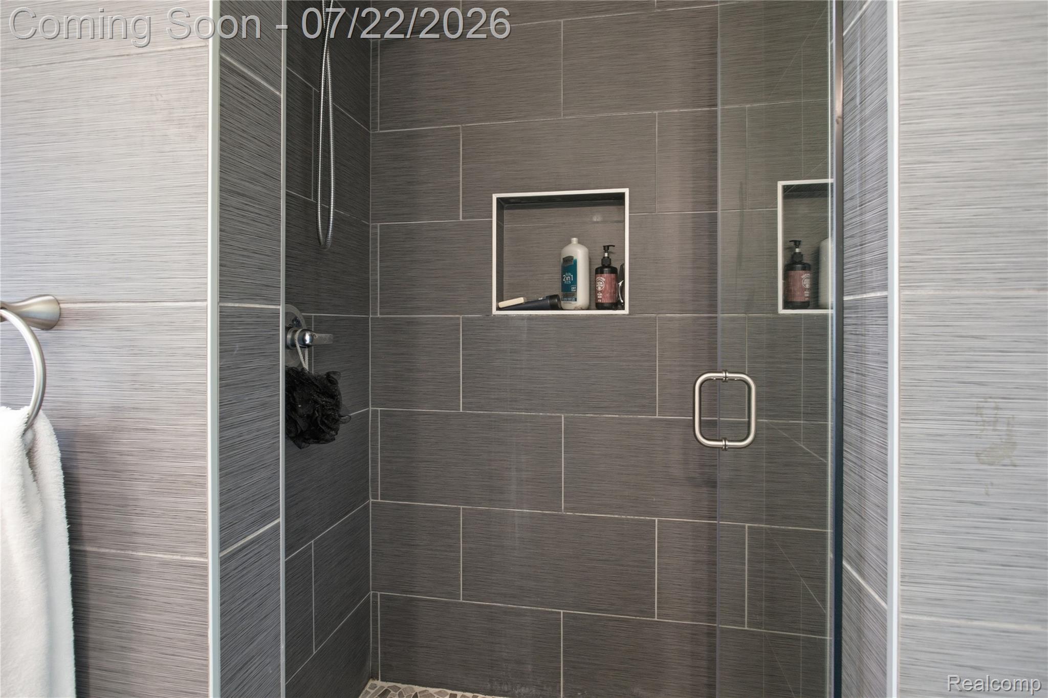 32127 Utica Road Fraser, MI 48026 - Photo 25 of 43 Tiled shower enclosure featuring a glass door with a polished chrome handle, two recessed wall niches, and a showerhead fixture