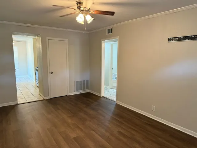 an empty room with wooden floor closet and windows