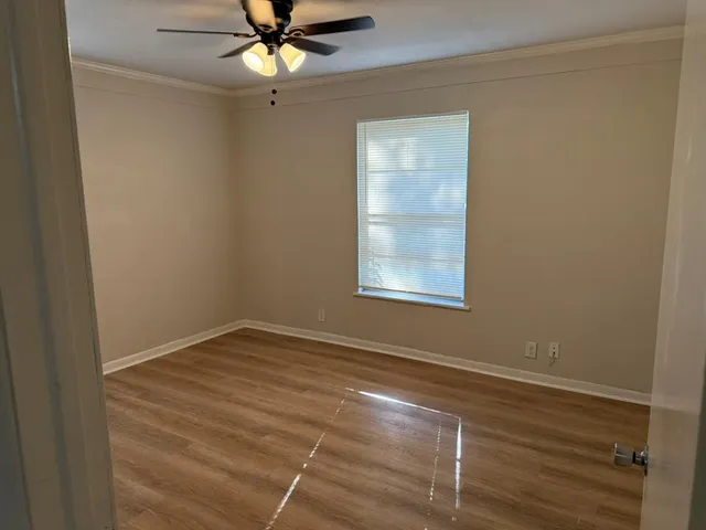 an empty room with a window and a fan