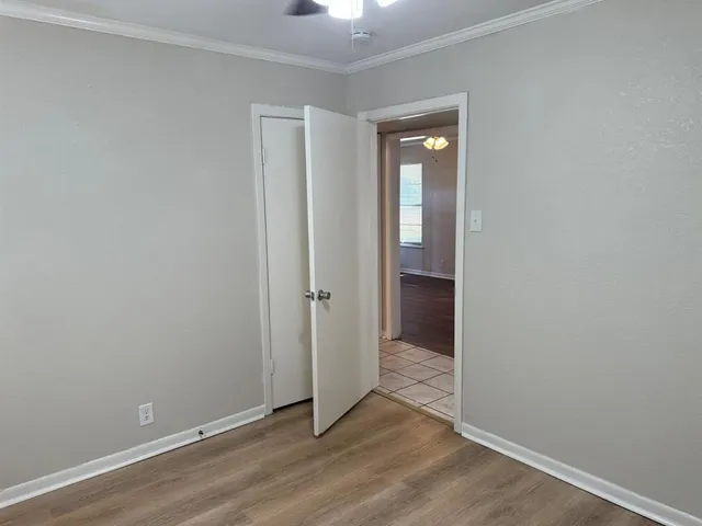 a view of an empty room with closet and wooden floor