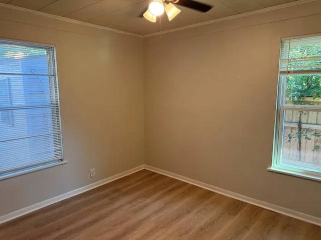 an empty room with windows and chandelier fan