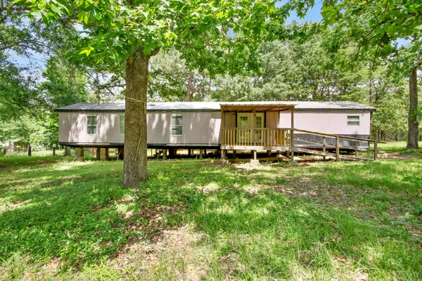 a backyard of a house with lawn chairs and a large tree