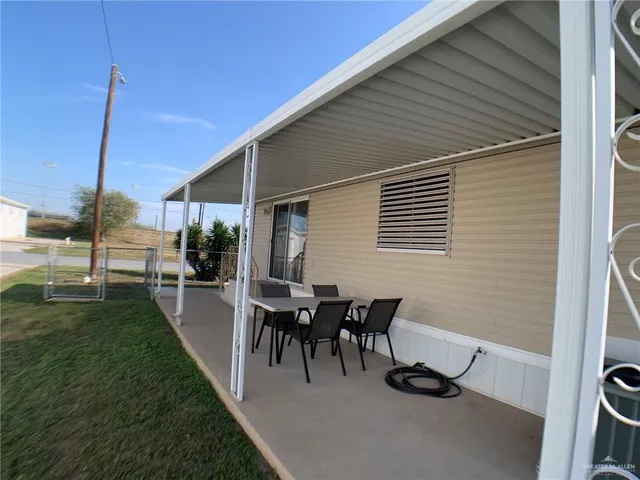 a view of a patio with table and chairs potted plants and floor to ceiling window