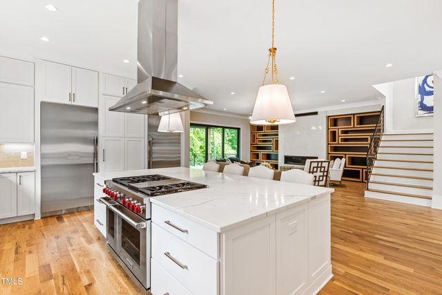 a kitchen with stainless steel appliances kitchen island granite countertop a table chairs and a wooden floor