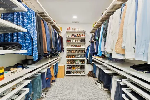 a view of walk in closet with clothes and shoes