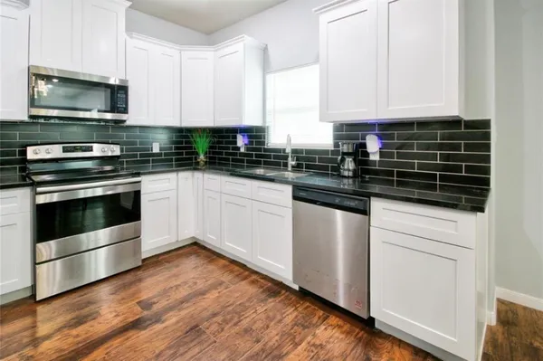 a kitchen with stainless steel appliances white cabinets a sink and a stove