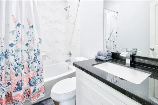a bathroom with a granite countertop sink a toilet and a bathtub