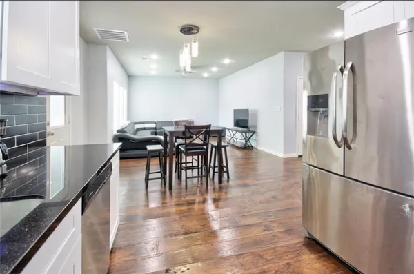 a kitchen with stainless steel appliances granite countertop a refrigerator a stove a kitchen island with a dining table and chairs