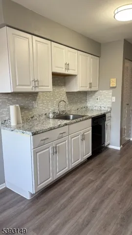 a kitchen with stainless steel appliances granite countertop a sink and cabinets with wooden floor