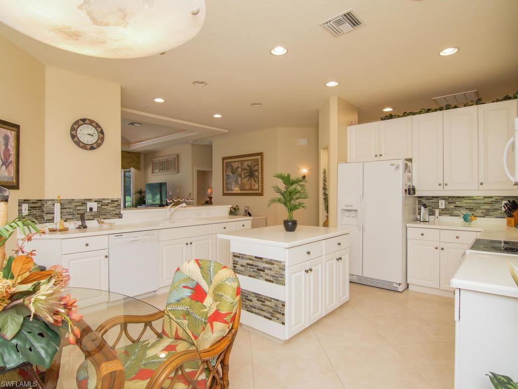 104 Napa Ridge Way Naples, FL 34119 - Photo 16 of 29 a large white kitchen with a white countertops a stove a dining table and chairs