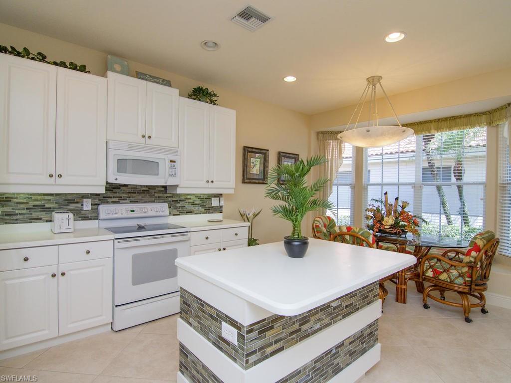 104 Napa Ridge Way Naples, FL 34119 - Photo 17 of 29 a kitchen with a dining table chairs and white cabinets