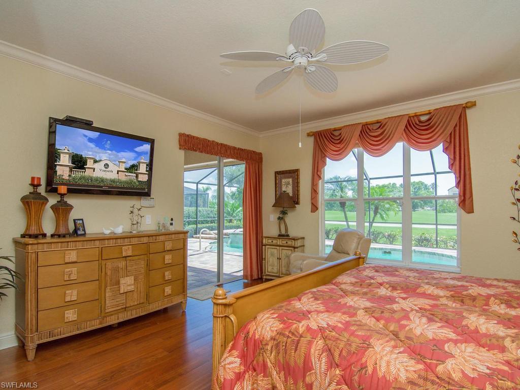 104 Napa Ridge Way Naples, FL 34119 - Photo 19 of 29 a bed room with a bed television and a large window