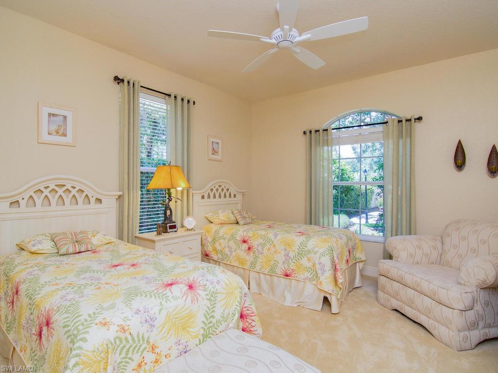 104 Napa Ridge Way Naples, FL 34119 - Photo 24 of 29 a bedroom with a large bed and a chandelier