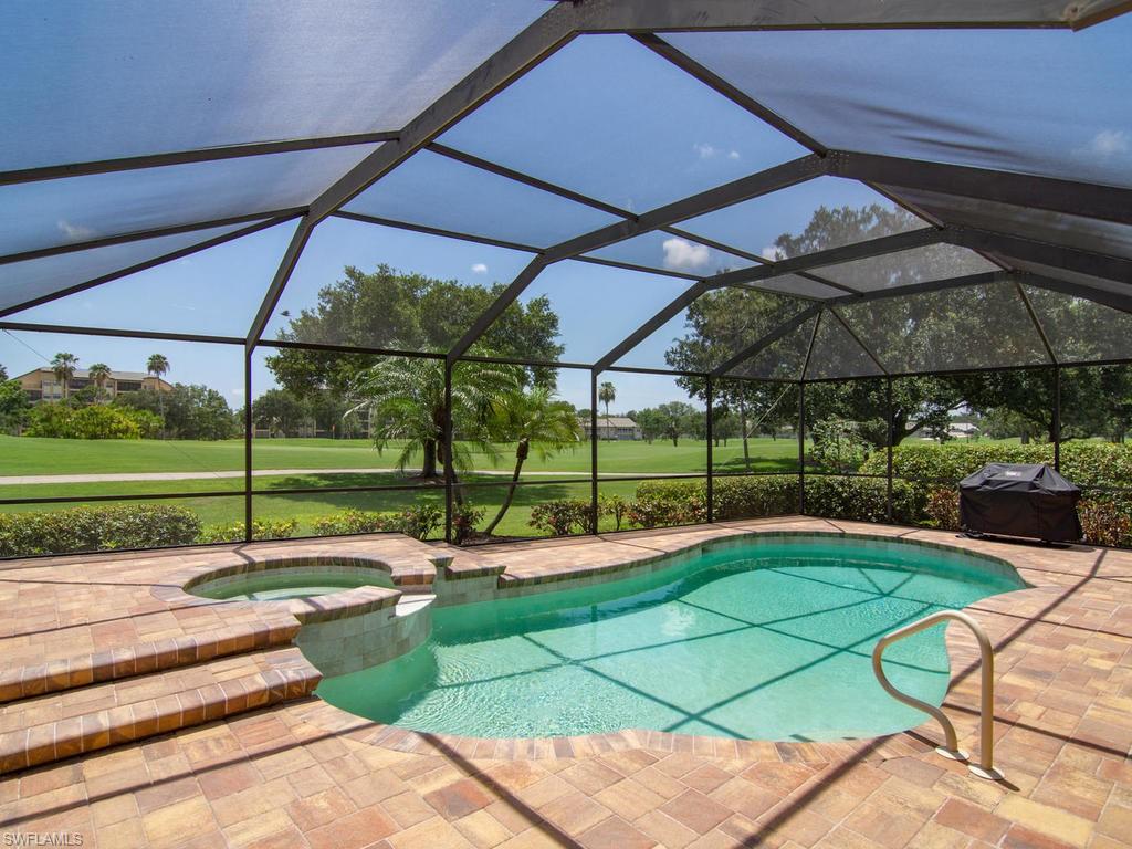 104 Napa Ridge Way Naples, FL 34119 - Photo 3 of 29 a view of a backyard with table and chairs under an umbrella