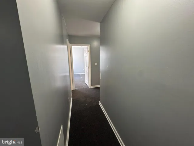 a view of a refrigerator in kitchen and an empty room