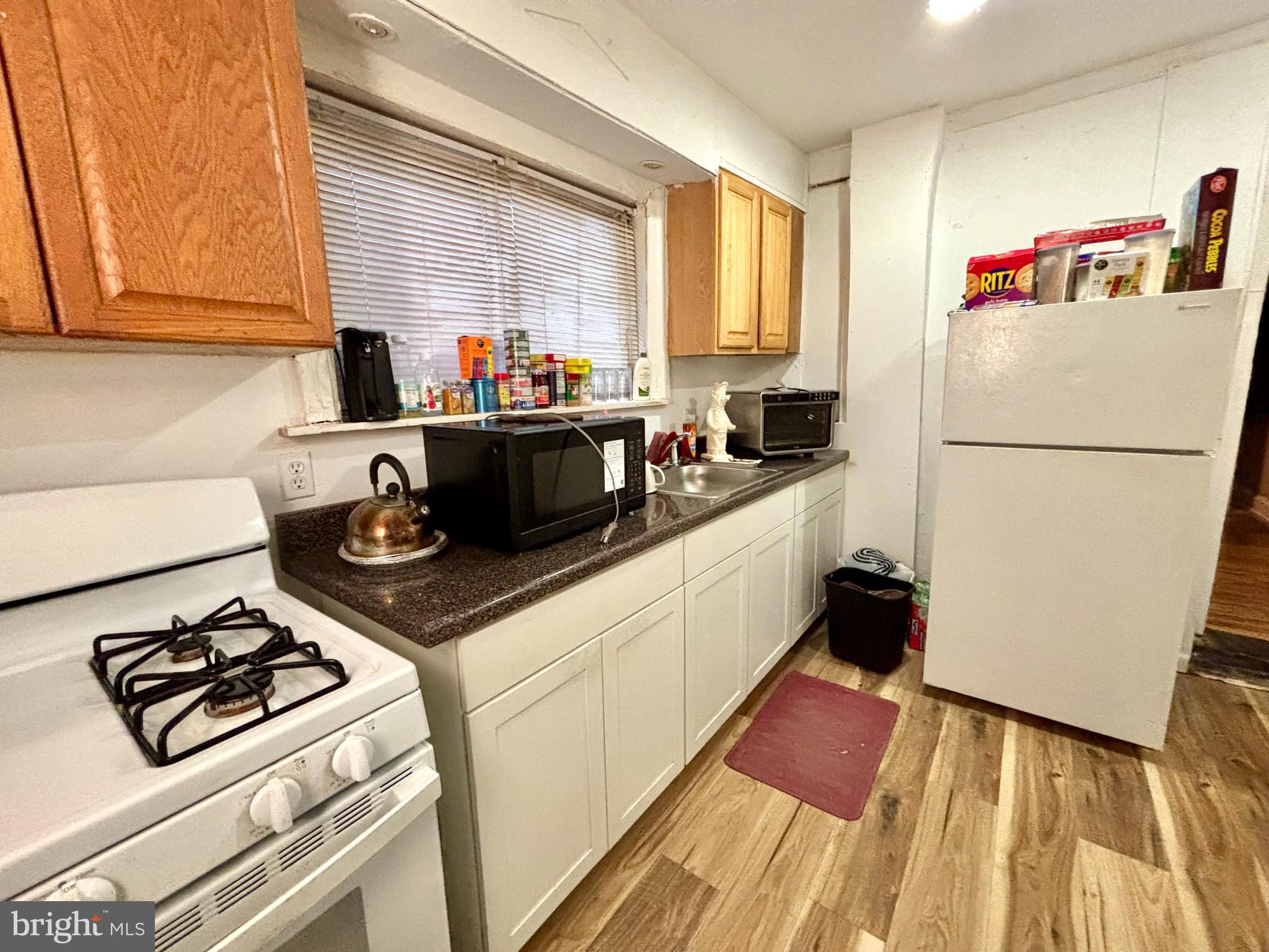 5144 West Stiles Street Philadelphia, PA 19131 - Photo 6 of 16 a white kitchen with a stove a refrigerator and a more cabinets