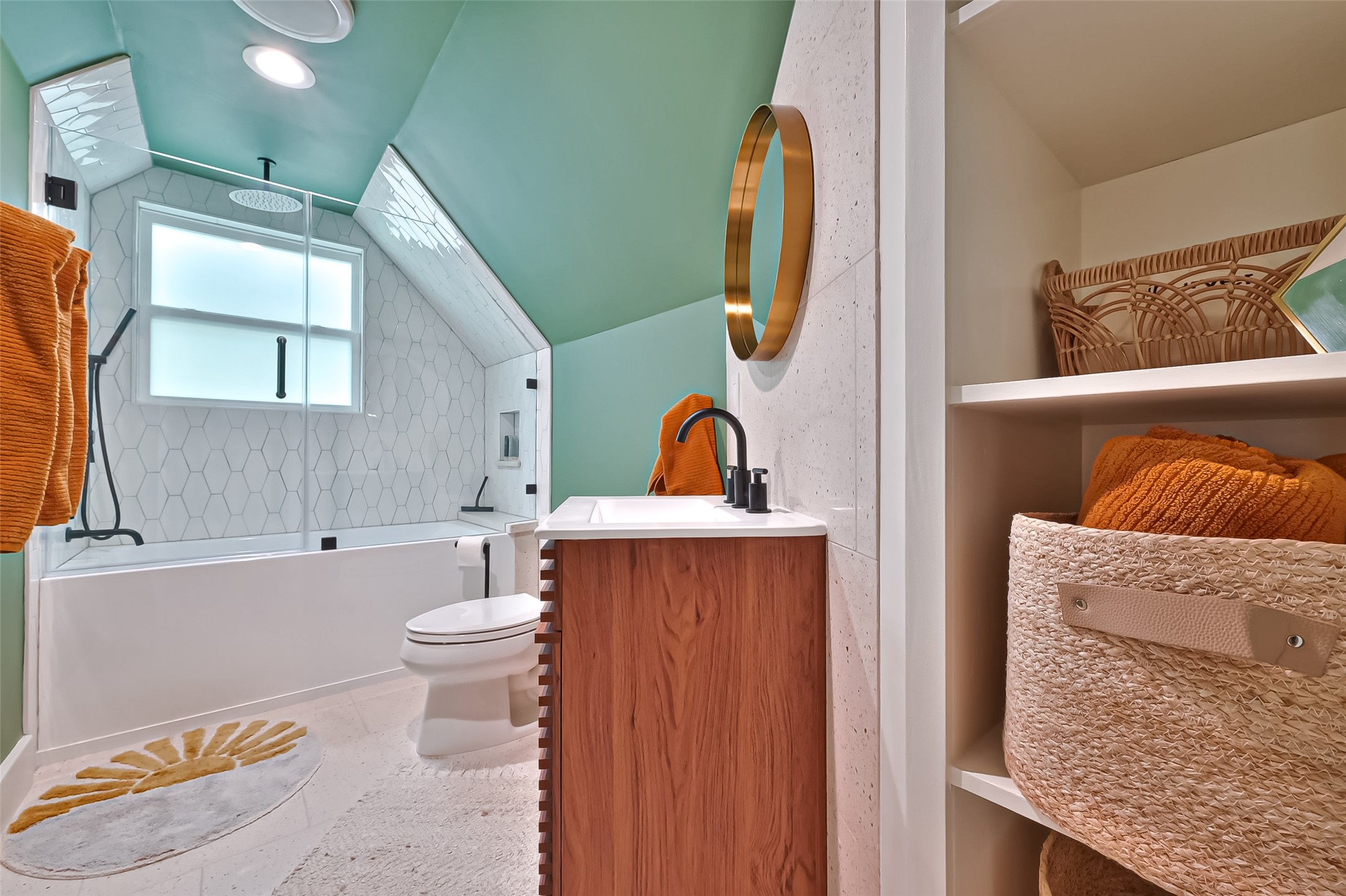 412 Sue Street Houston, TX 77009 - Photo 15 of 19 This upstairs full bathroom features a modern design, mint green walls, and a white hexagonal tile shower. It includes a sleek wooden vanity and built-in shelving.