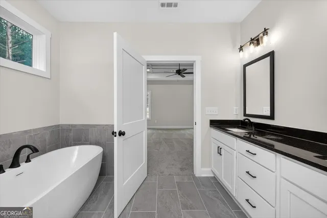 a spacious bathroom with a granite countertop sink mirror and bathtub