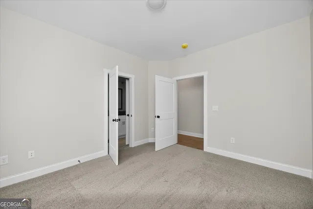 a view of an empty room with window and kitchen view