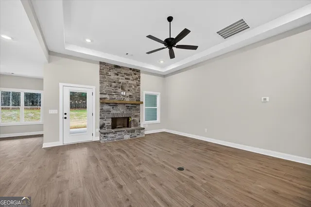 a view of a livingroom with a fireplace a ceiling fan and wooden floor