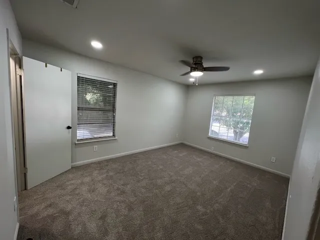 en empty room with windows and ceiling fan