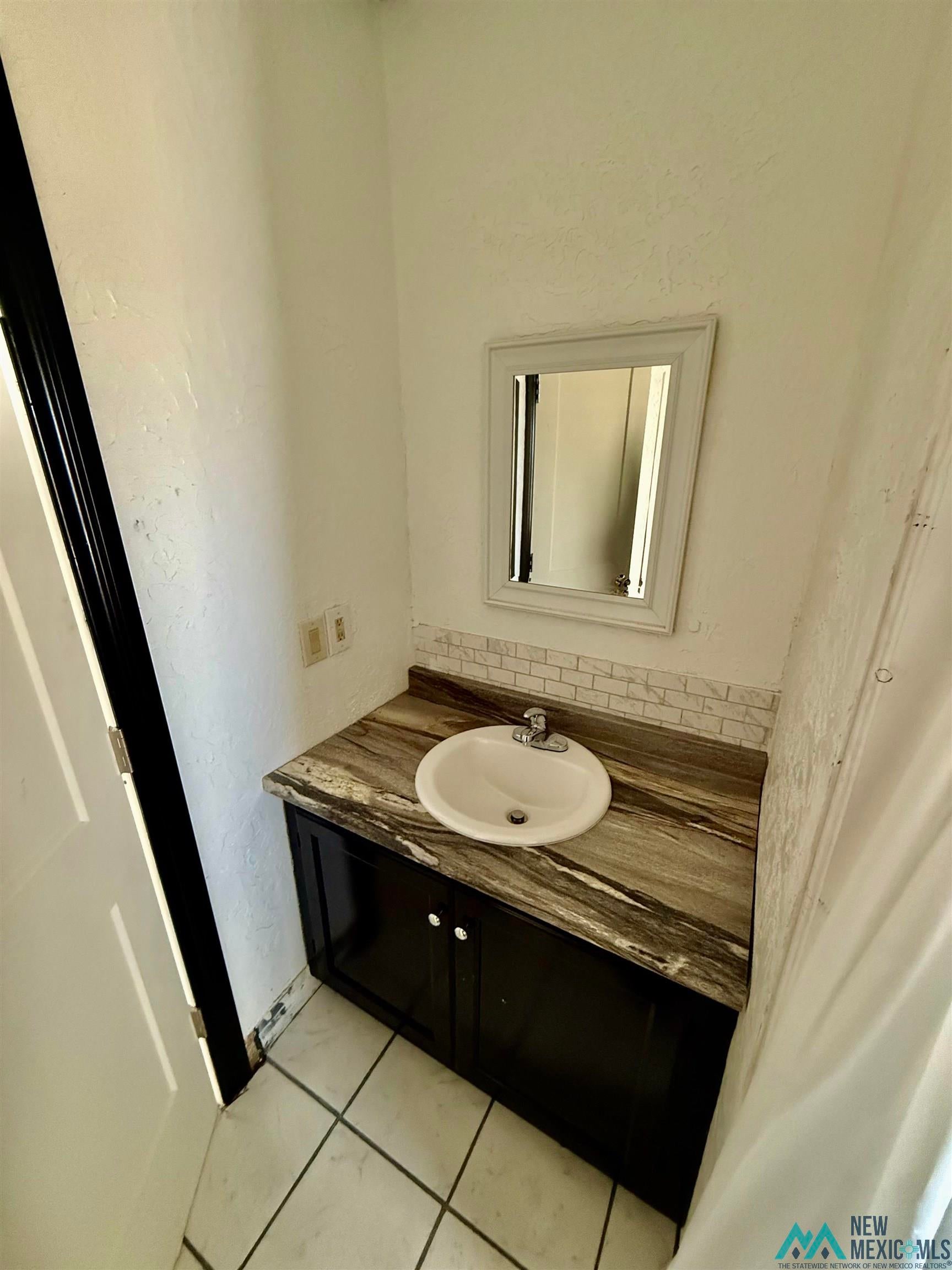 207 Chuckwagon Road Carlsbad, NM 88220 - Photo 9 of 19 Bathroom with vanity, light tile patterned flooring, and a textured wall