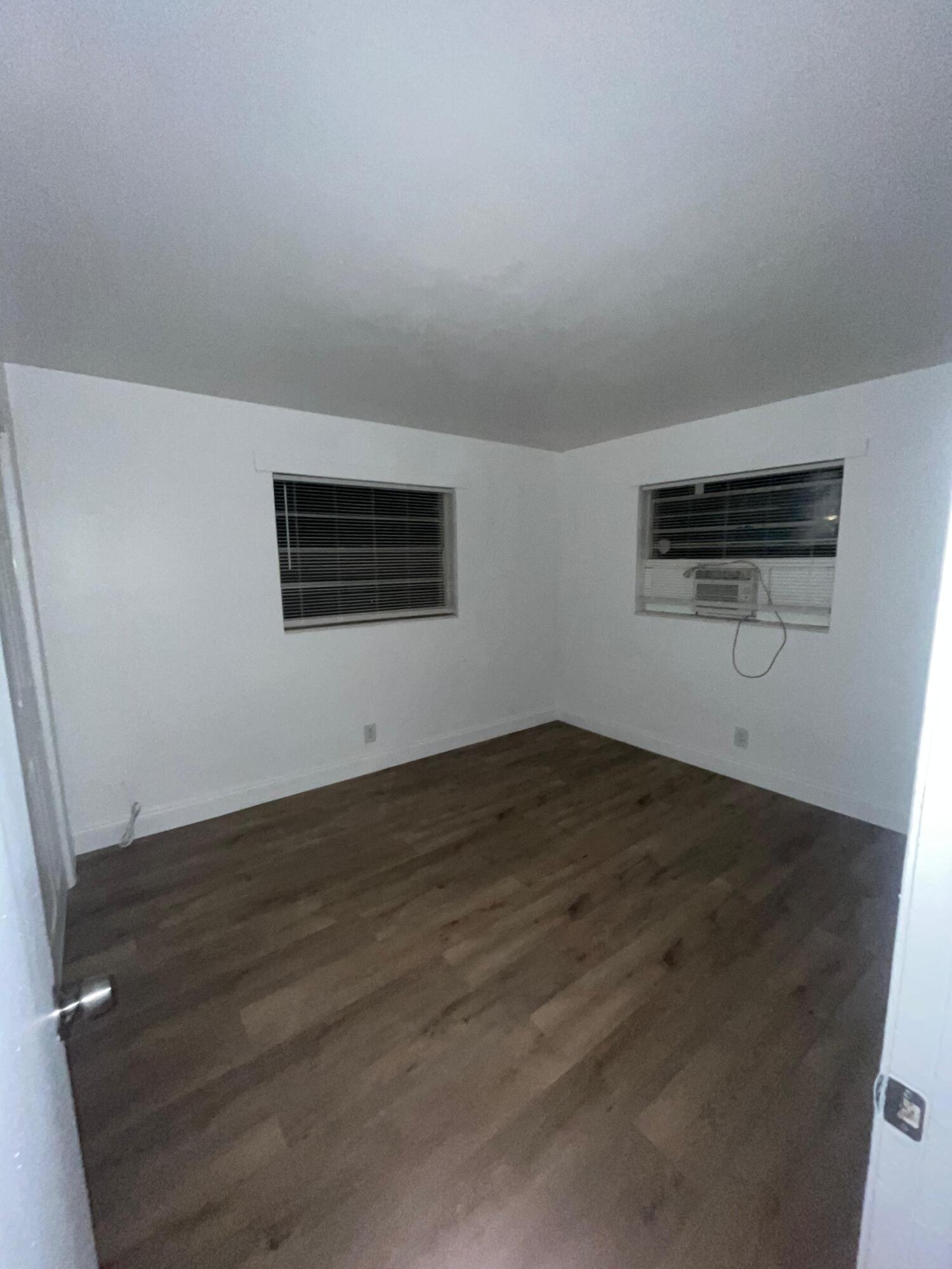 1245 West 35th Street, Unit 4 Riviera Beach, FL 33404 - Photo 8 of 11 an empty room with wooden floor and windows