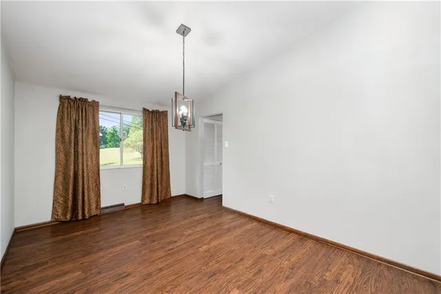 a view of empty room with wooden floor and window