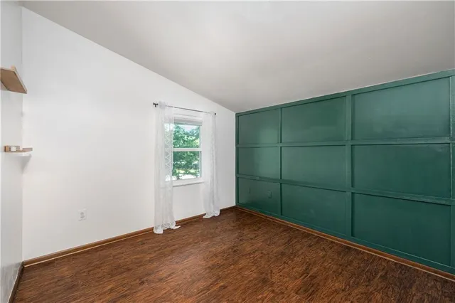a view of empty room with wooden floor and window