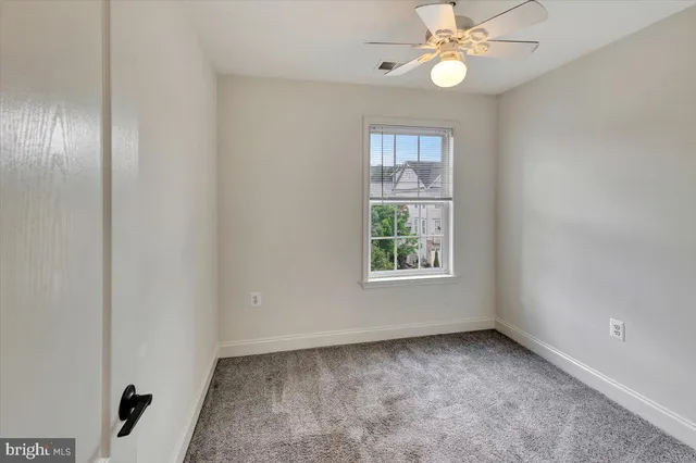 an empty room with windows and fan