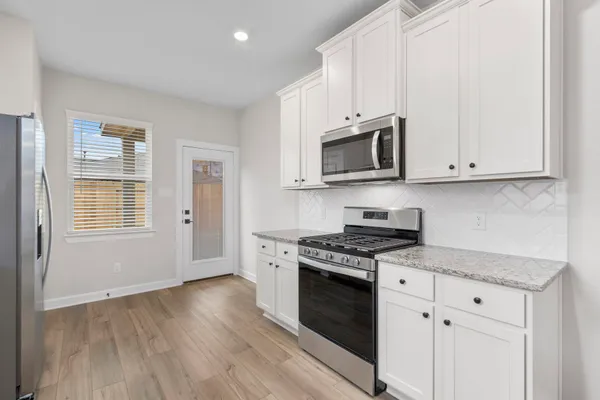 a kitchen with granite countertop wooden cabinets and a stove top oven