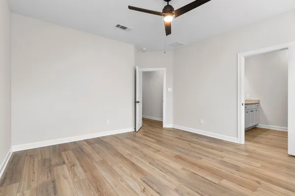 an empty room with wooden floor and a ceiling fan