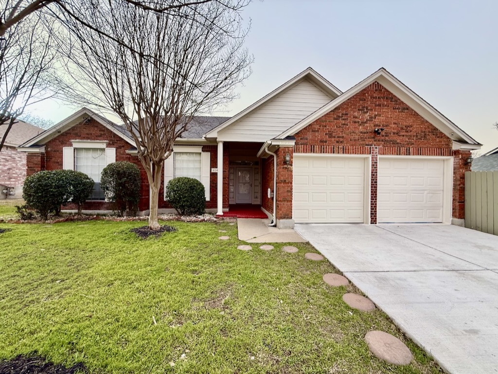 Single story home featuring brick siding, concrete driveway, a front yard, fence, and a garage