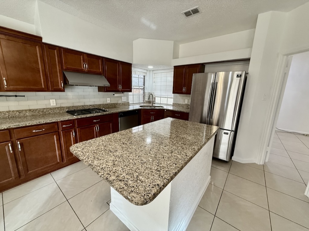 604 Cactus Bend Drive Pflugerville, TX 78660 - Photo 11 of 29 Kitchen featuring light tile patterned floors, a sink, stainless steel appliances, under cabinet range hood, and backsplash