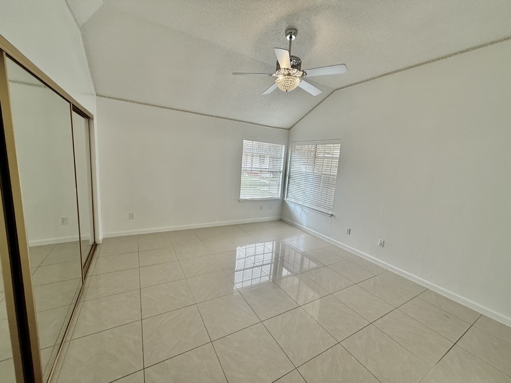 604 Cactus Bend Drive Pflugerville, TX 78660 - Photo 17 of 29 Unfurnished room featuring a textured ceiling, ceiling fan, lofted ceiling, light tile patterned flooring, and baseboards