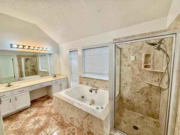 a bathroom with a bathtub and a double vanity sink mirror